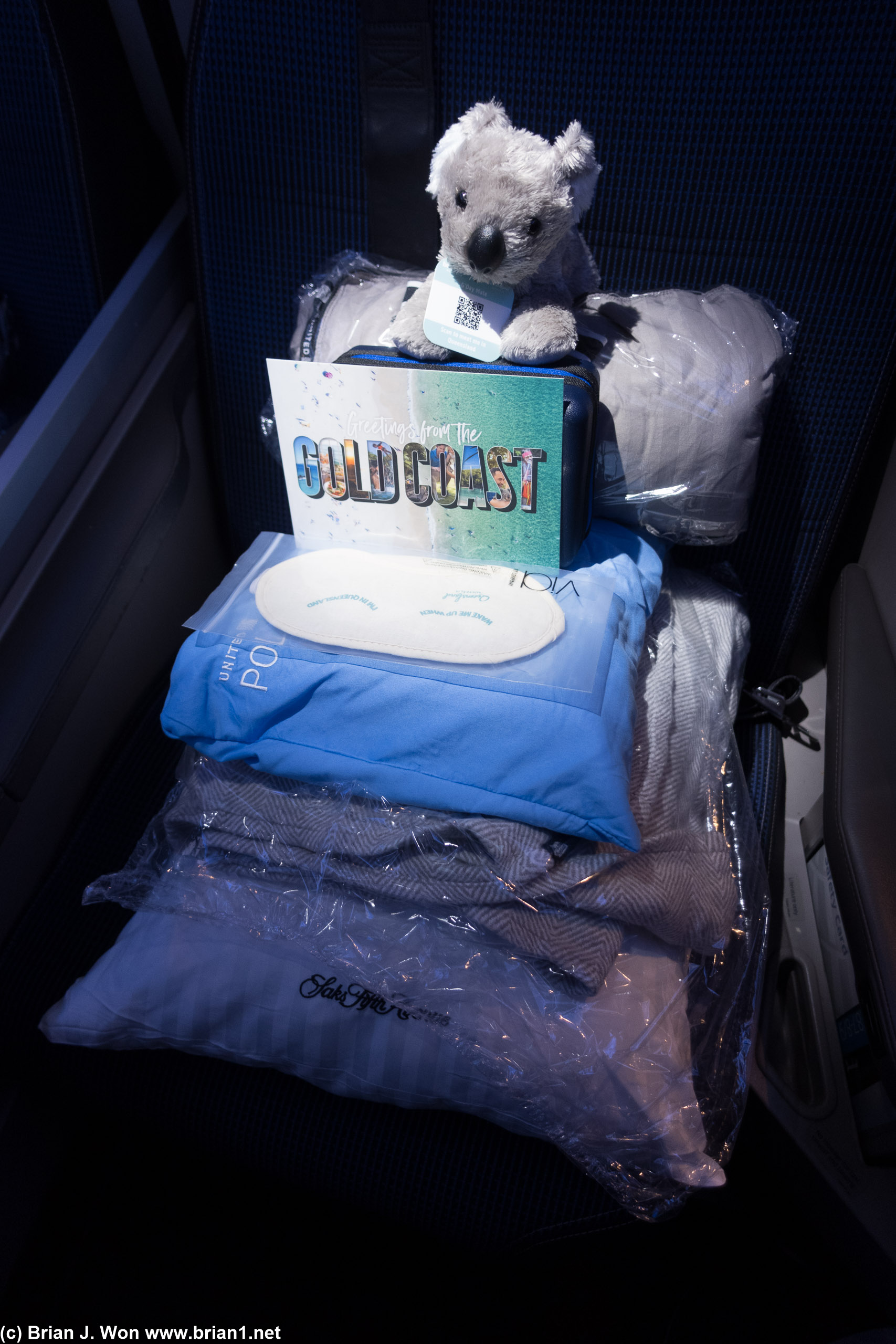 Polaris amenities at the seat, including an inaugural flight special koala, Gold Coast tourism flyer, and eye mask.