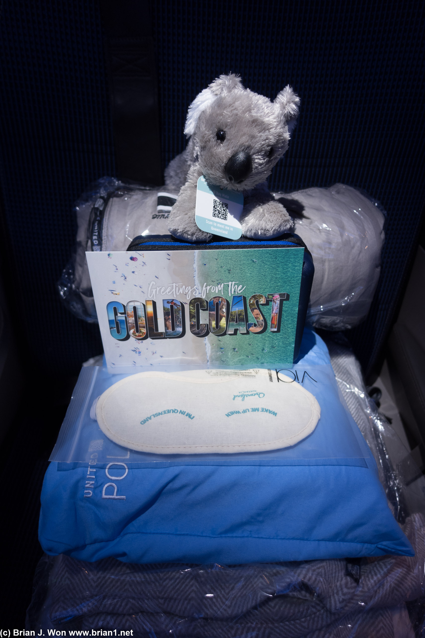 Polaris amenities at the seat, including an inaugural flight special koala, Gold Coast tourism flyer, and eye mask.
