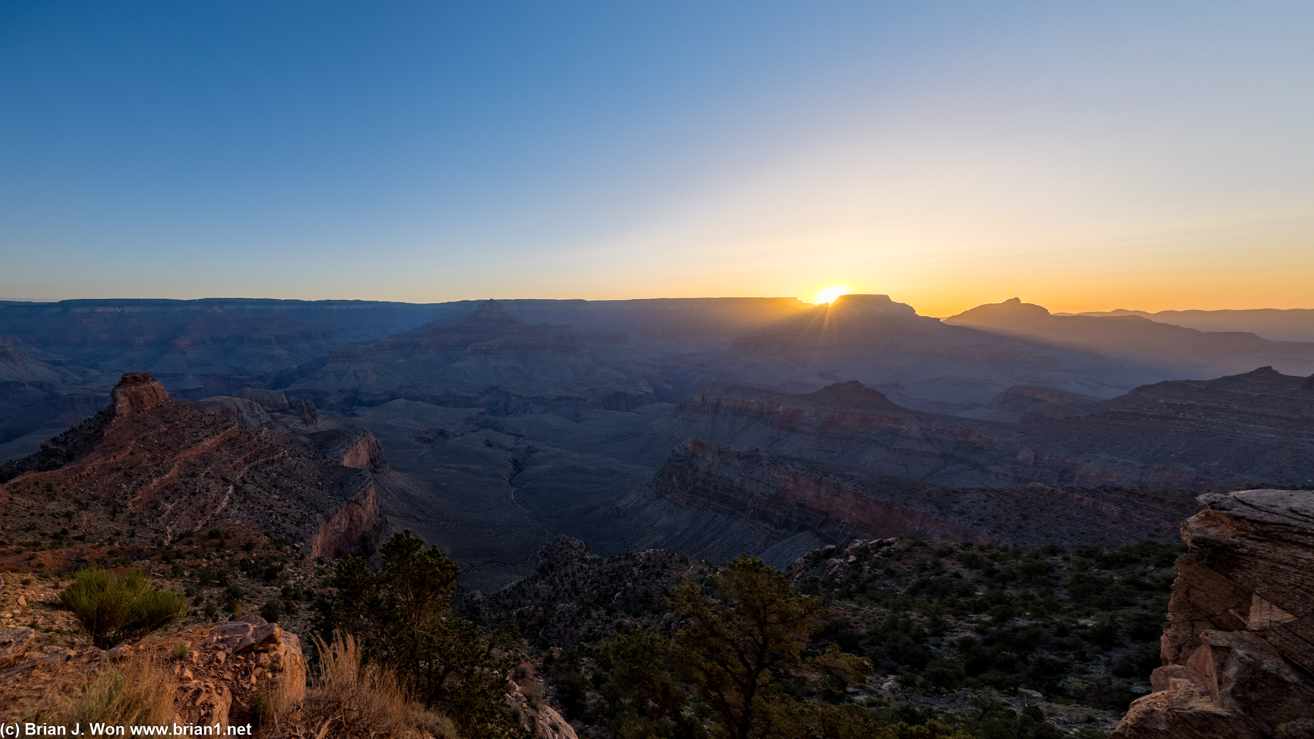 Sunrays shoot through the dips in the rim.