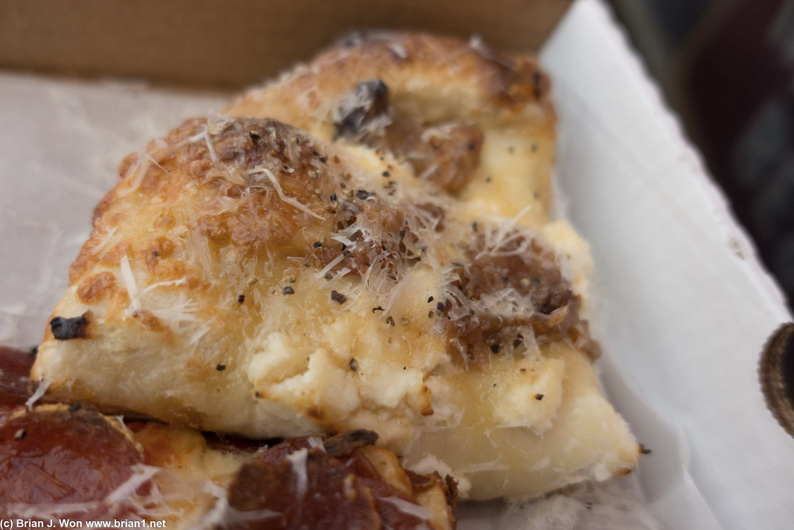 Close-up of the Hot Jimmy, ricotta, mozzarella, hot italian sausage, pepper, parmesan, hot honey.