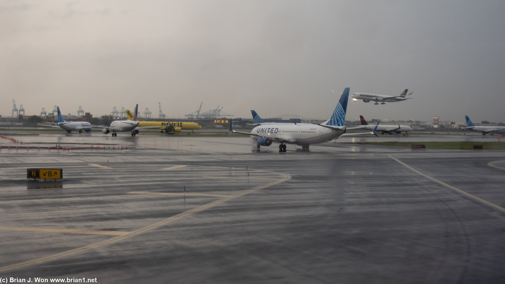 At least 8 airplanes waiting to take off, as a Singapore A350-900 comes in for landing.