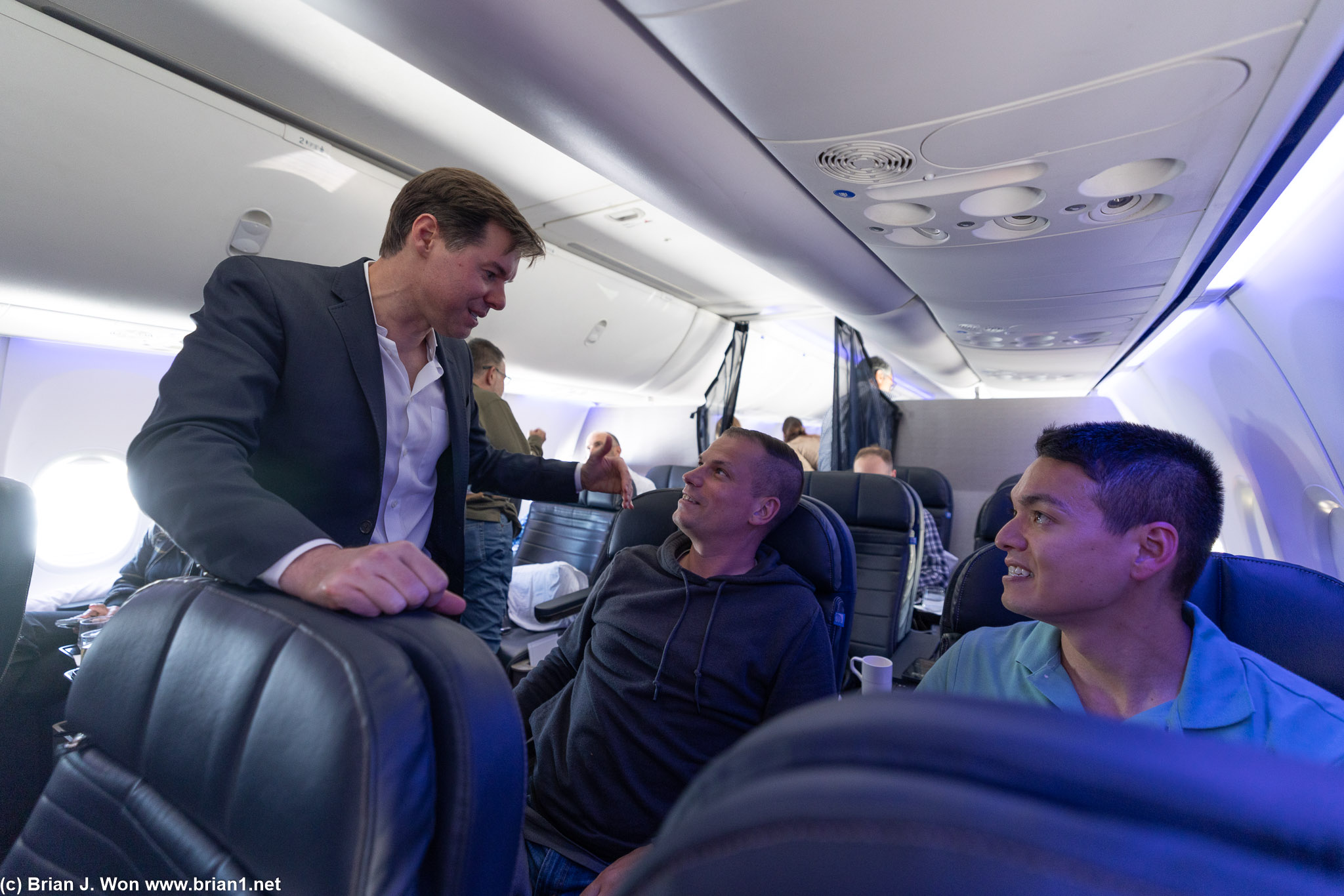Senior Vice President Patrick Quayle chatting with passengers in premium economy (Premium Plus).
